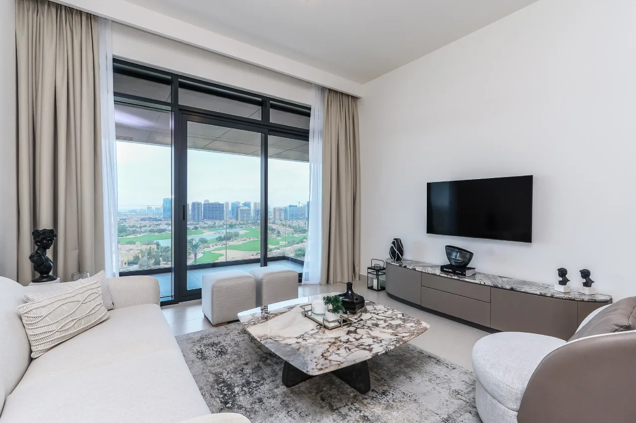 Living room at Vista by Prestige One, with balcony windows overlooking Dubai Sports City